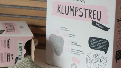 Zwei Kartons Katzenstreu, er liegt geöffnet auf der Seite und Streu rieselt heraus