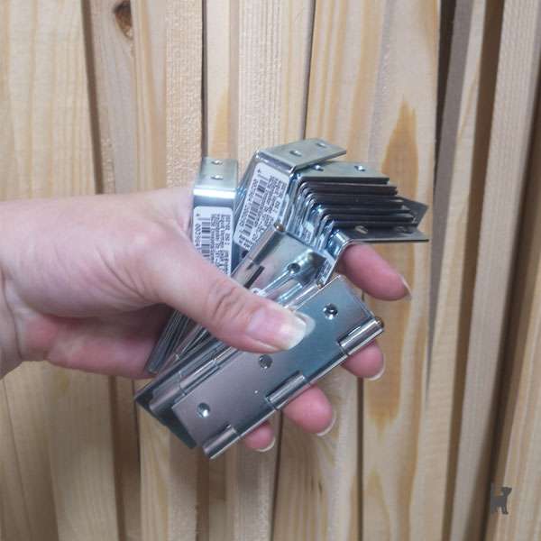 Das Foto zeigt im Hintergrund Holzlatten. Im Vordergrund eine Hand, die verschiedene Winkel hält