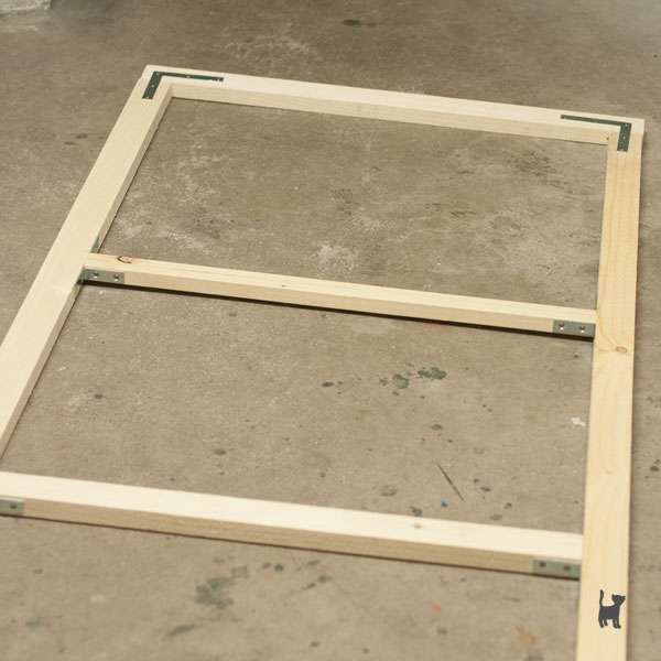 Auf dem Foto liegt ein Teil der fertig zusammengebauten Gittertür auf dem Boden. Der Fokus liegt dabei auf den Querlatten zur Stabilisierung.